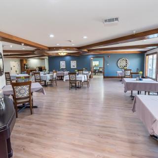 A spacious restaurant dining area with wooden floors, neatly arranged tables and chairs.