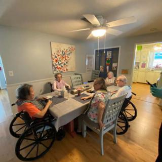 A group of seniors enjoying a meal together at a dining table in a care home.