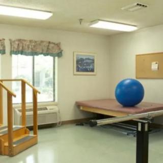 A physical therapy room with a blue exercise ball, parallel bars, and stairs.