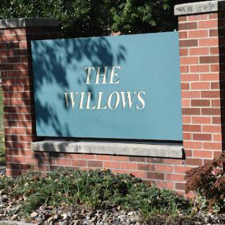 A welcoming sign for 'The Willows', set against a backdrop of lush greenery.