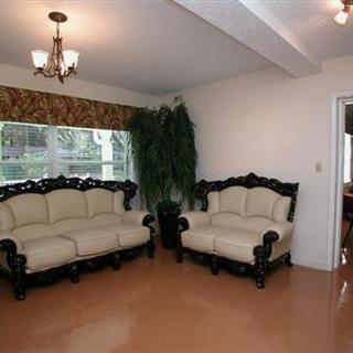 A cozy living room with elegant sofas and a chandelier, featuring large windows and a decorative plant.
