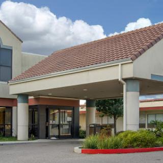 A welcoming entrance to a hospitality building under a partly cloudy sky.