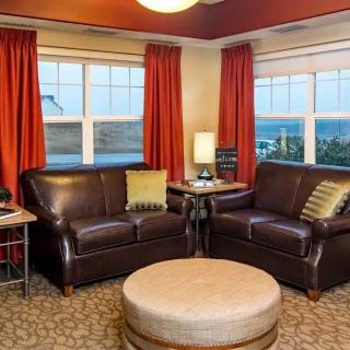 A cozy living room with leather sofas and bright red curtains overlooking a scenic view.