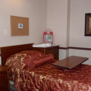 A cozy bedroom with a red patterned comforter and wooden furniture.