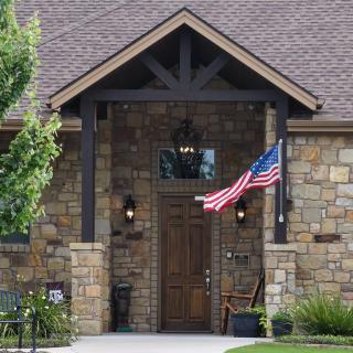 A welcoming house entrance with a stone facade and an American flag displayed prominently.