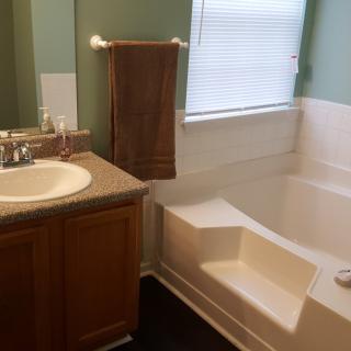 A bathroom featuring a sink with a towel and a bathtub near a window.