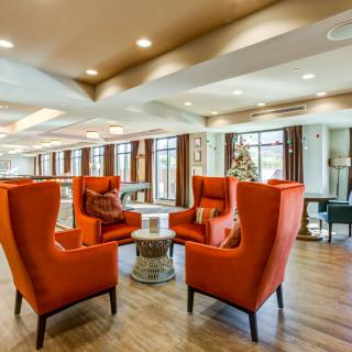 A modern lounge area with orange armchairs and abundant natural light.