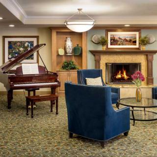 A cozy living room with a grand piano, fireplace, and comfortable seating.
