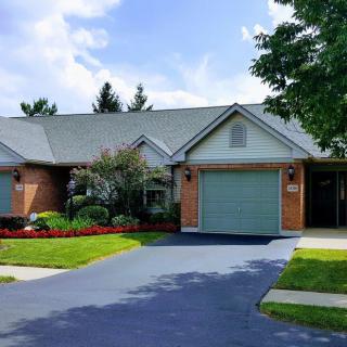 A suburban brick house with a garage and landscaped front yard.