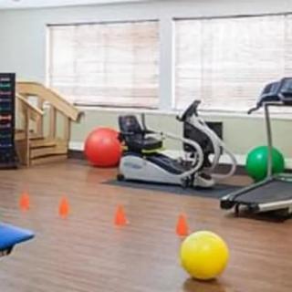 A fitness center with various exercise equipment including a treadmill, elliptical machine, and colorful exercise balls.