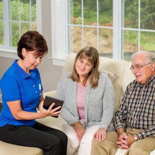 A healthcare professional discusses important information with a couple in a comfortable home setting.