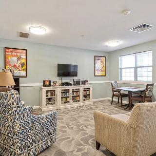 A cozy living room with armchairs, bookshelves, and a television set.