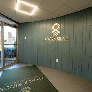 The modern lobby of Wyack Ridge featuring a stylish green accent wall and branded signage.