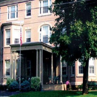 A historic residential building with a prominent entrance and surrounding greenery.