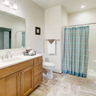 A modern and spacious bathroom featuring a wooden vanity, a clean sink area, and a patterned shower curtain.