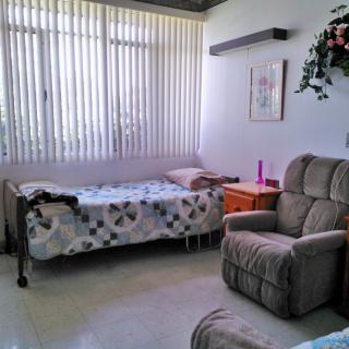A cozy room with a bed and armchair, decorated with flowers and artwork.