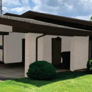 A modern house with a distinct architectural design featuring clean lines and a lush green lawn.