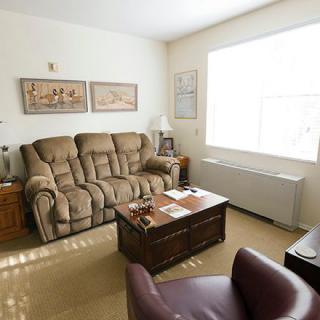 A cozy living room with a comfortable sofa, armchair, and coffee table positioned near a large window.