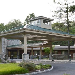 A welcoming entrance to a modern building surrounded by lush greenery.
