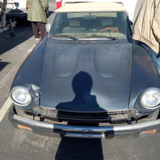 A classic vintage convertible car with a hint of rust, parked in the sunlight.