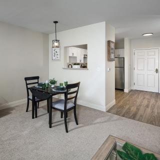 A modern apartment's open dining area connected to the kitchen, featuring a table with chairs and stylish lighting.