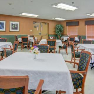 A neatly arranged dining area with tables and chairs, featuring tablecloths and decorative centerpieces.