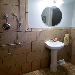 A tiled bathroom with a pedestal sink, mirror, and shower.