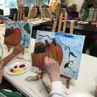 Participants enjoy a painting class focusing on autumn themes, creating their own pumpkin masterpieces.
