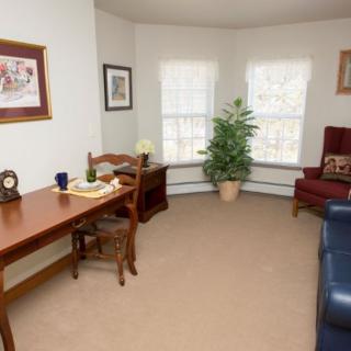 A cozy living room with a wooden desk, chair, and an indoor plant by the window.