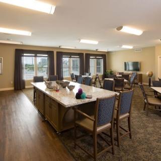 A spacious dining area with a kitchen island, surrounded by chairs and large windows.