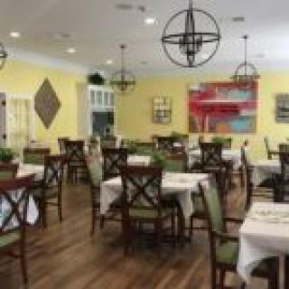 An inviting restaurant dining area with neatly arranged tables and chairs, warm lighting, and colorful wall decorations.
