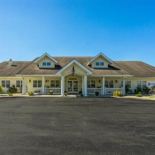 A large residential building with a spacious driveway under a clear blue sky.