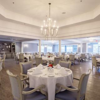 An elegant dining area with a chandelier and neatly set tables, exuding a sophisticated ambiance.