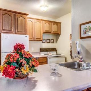 A cozy kitchen featuring wooden cabinets, a white refrigerator, and a bouquet of flowers on the countertop.