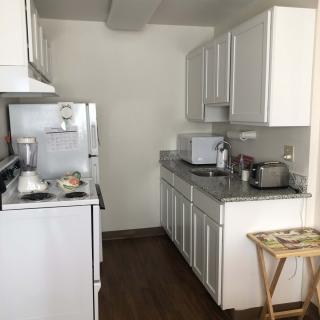 A compact kitchen with white cabinets, a refrigerator, stove, and microwave.