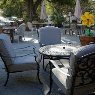 A serene outdoor cafe setting with comfortable seating and vibrant flowers.