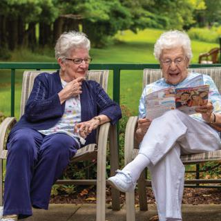 Two elderly women enjoying a peaceful moment together in nature, sharing laughter and stories.