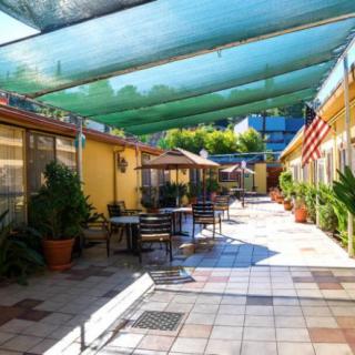 A sunny courtyard with outdoor seating, shaded by green canopies.