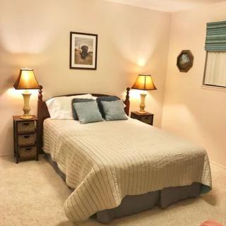 A cozy bedroom with a bed flanked by nightstands and lamps, featuring soft lighting and elegant decor.