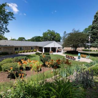 A beautifully landscaped garden with a building in the background under a clear blue sky.