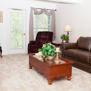 A bright living room with a sofa, armchair, and wooden coffee table.