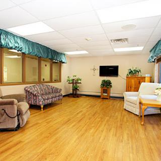 A spacious and well-lit living area featuring comfortable sofas, a television, and decorative plants.
