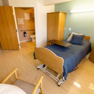A clean and well-organized hospital room featuring a bed, a small table, and essential furniture.