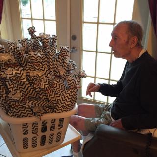 A man sits indoors, looking at a basket filled with patterned items.