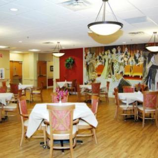 An elegantly set dining room with multiple tables and chairs, adorned with decorations on the walls.
