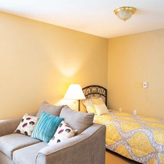 A cozy bedroom with a single bed, sofa, and warm lighting.