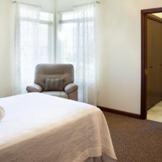 A cozy bedroom with a comfortable chair and natural light streaming through the windows.