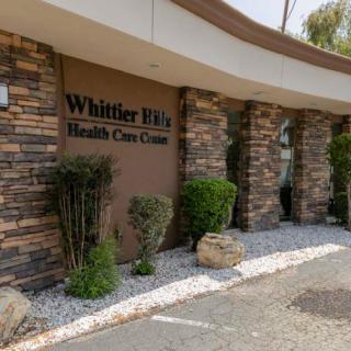Exterior view of Whittier Hills Health Care Center with stone facade and landscaped surroundings.