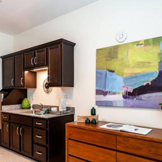 A modern kitchen with dark cabinets and colorful artwork on the wall.