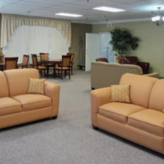 A spacious living room with beige sofas and a dining area in the background.
